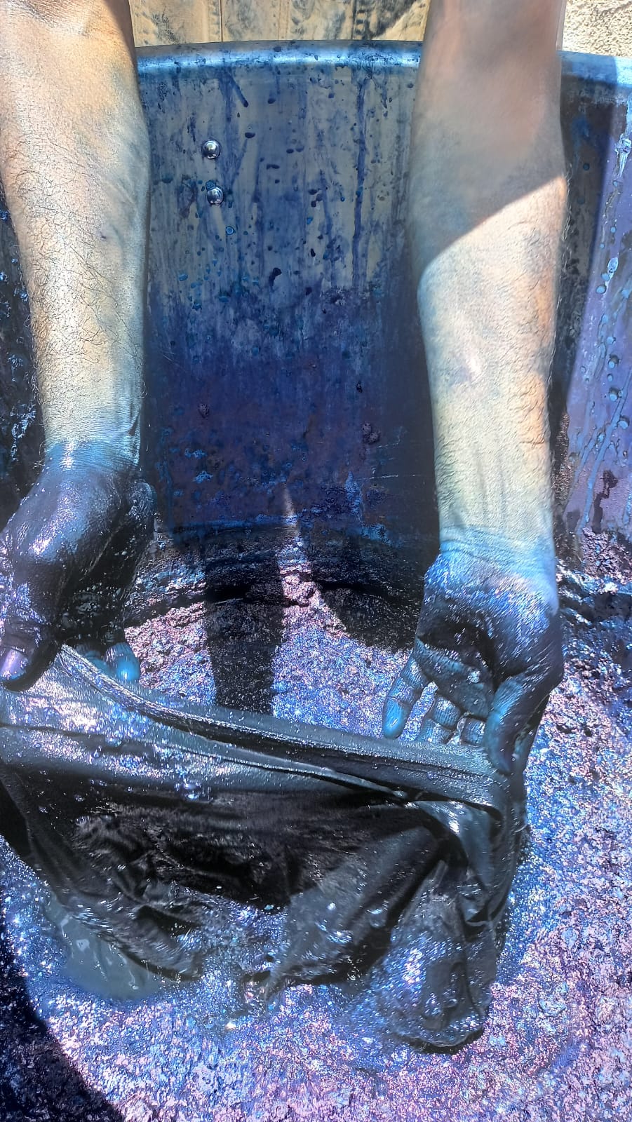 Hands working with fabric in an indigo dye bath